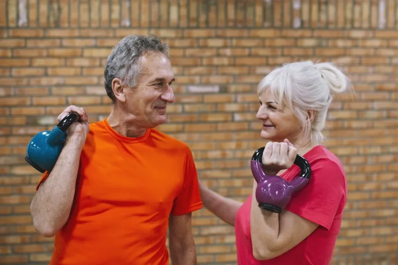 Senior couple training with kettlebells, smiling